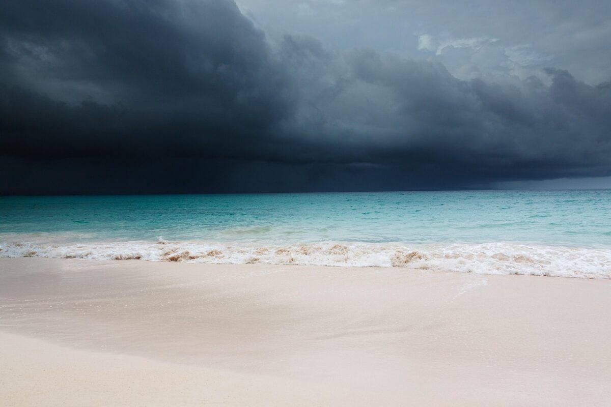 A storm approaches a white sand beach